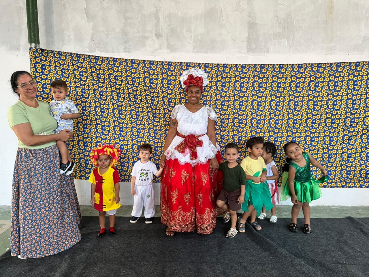 Professora em traje de baiana com as crianças pequenas