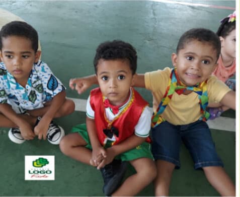 Três meninos fantasiados sentados juntos na quadra do colégio