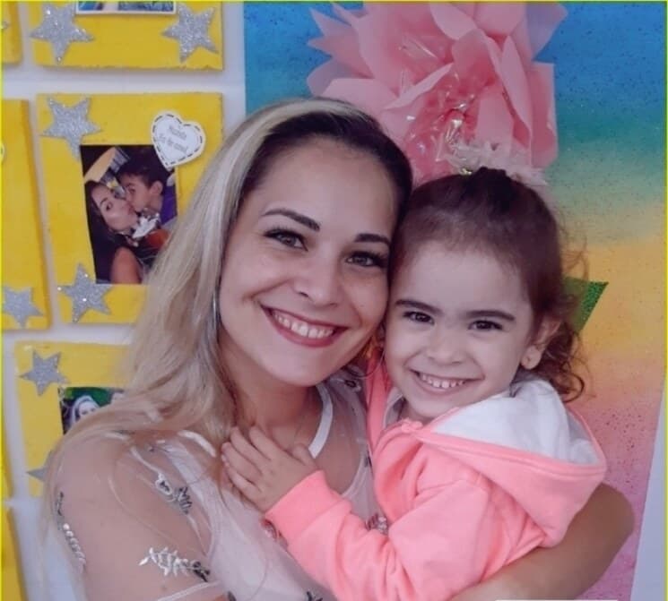 Professora e aluna abraçadas na entrada do Colégio Logo