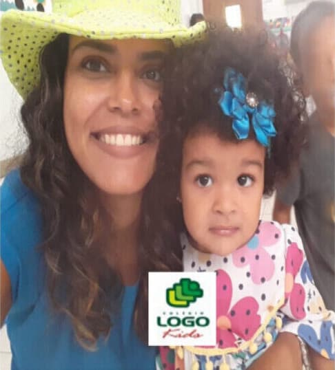 Professora com uma aluna no colo, as duas sorrindo